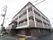 茶色やグレーを基調とした外壁のマンションが建っている。４階建てで、２階から上の部分はベランダも付いている。