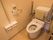 トイレには温水洗浄便座が採用されている。壁に操作ボタンがあるので押しやすい。可動式のひじ掛けと背もたれがある。