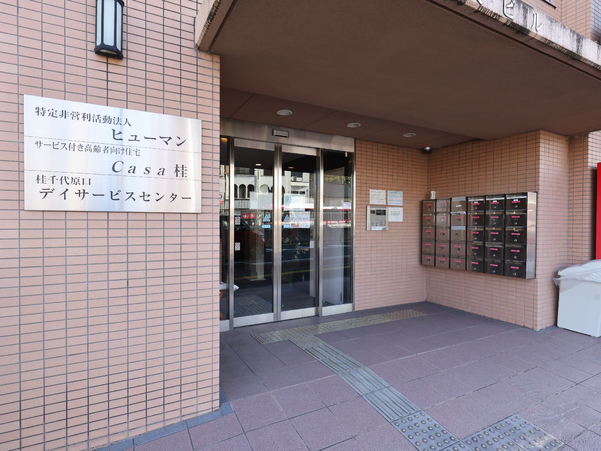 高齢者の方にタオルをかけてマッサージしているスタッフと振り返りながら会話する女性の様子