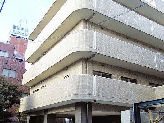 角フロアにベランダが付いたライトグレーのしっかりとした建物。周囲には背の高い建物が多くある。