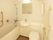ユニット型の浴室には白い浴槽とシンプルなトイレが付き、トイレと浴槽の横には手すりが付いている。シャワーや鏡もあり、タオル掛けにはタオルがある。