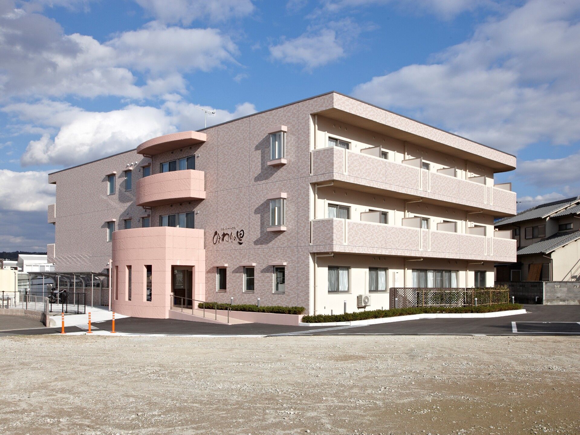 3階建ての建物はピンクがかったベージュで重厚感のある造り。敷地は広く、グラウンドのような場所もある。建物の2階と3階部分にはベランダもある。