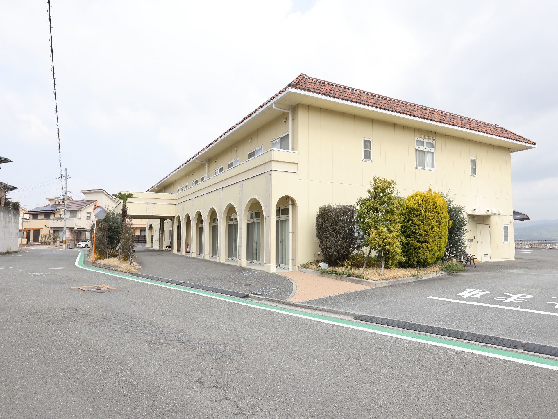 ２階建ての建物は日当たりのいい場所に建っていて、ベージュの外壁。明るい雰囲気。