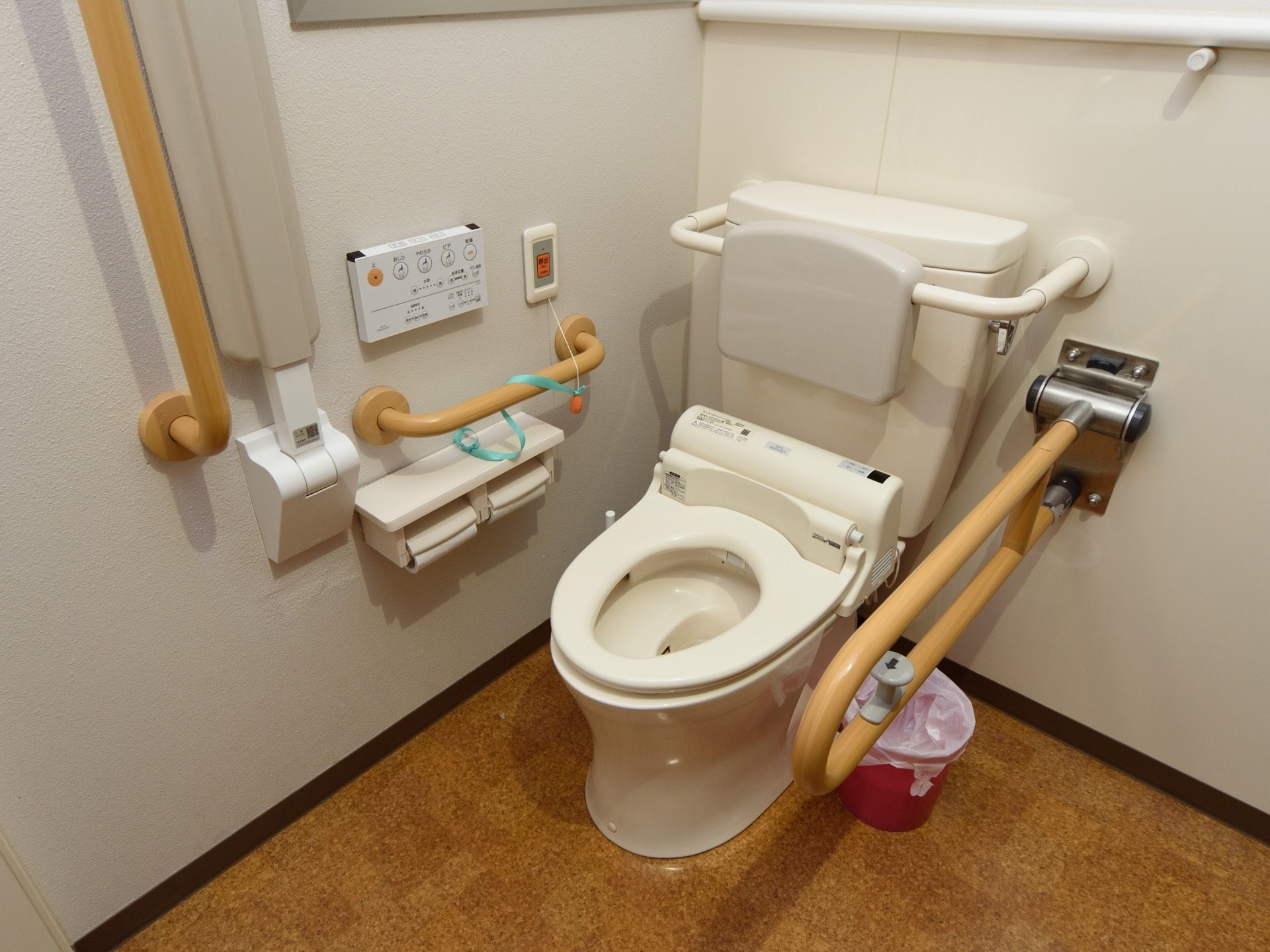 便座の右側には、跳ね上げ式の手すりが世知されており、その下にはビニール袋のかかったゴミ箱が置いてある。