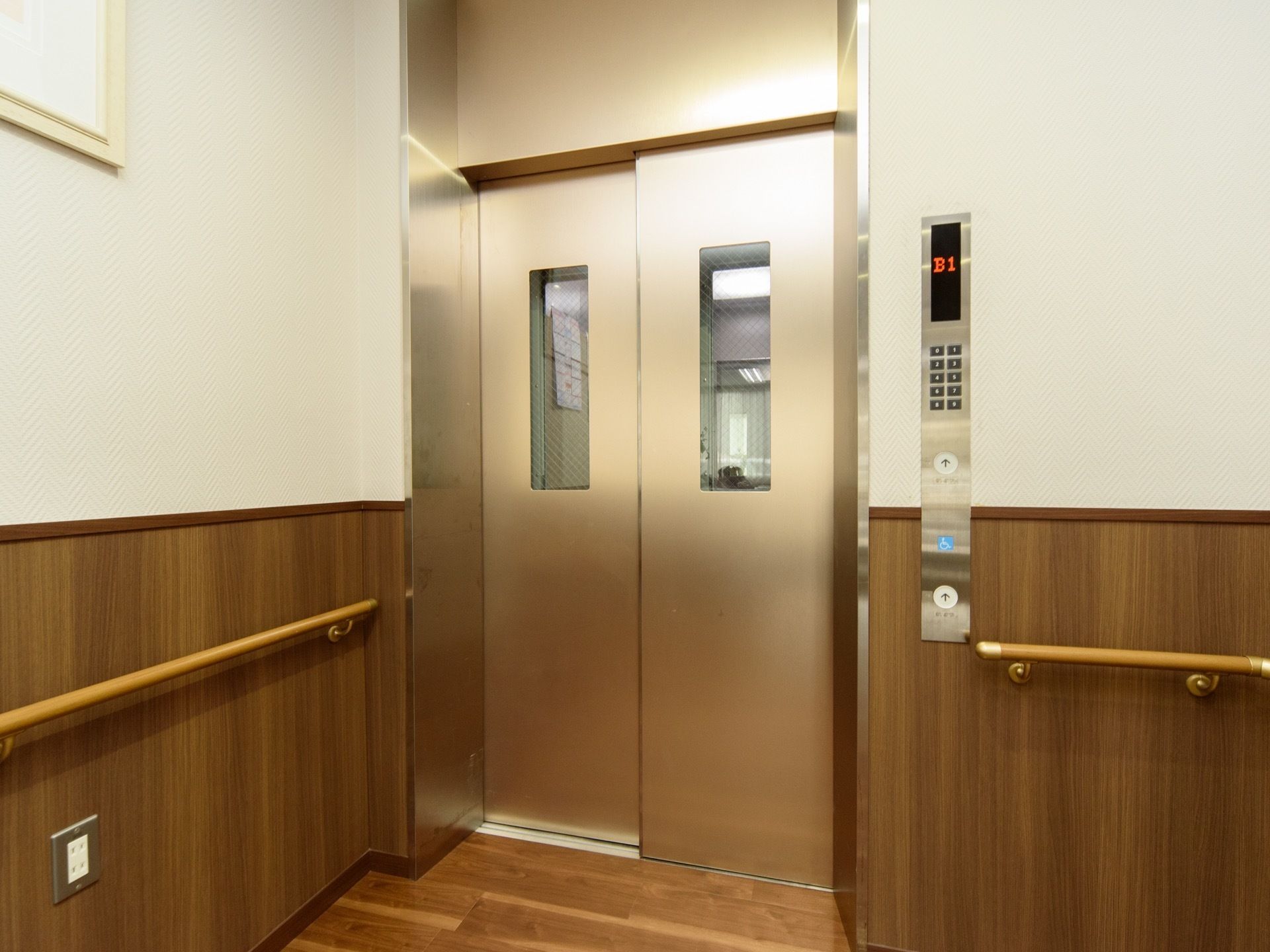 左の隅にエレベーターが設置されており、壁には小窓が付けられている。近くの壁には、手すりとともにコンセントがある。
