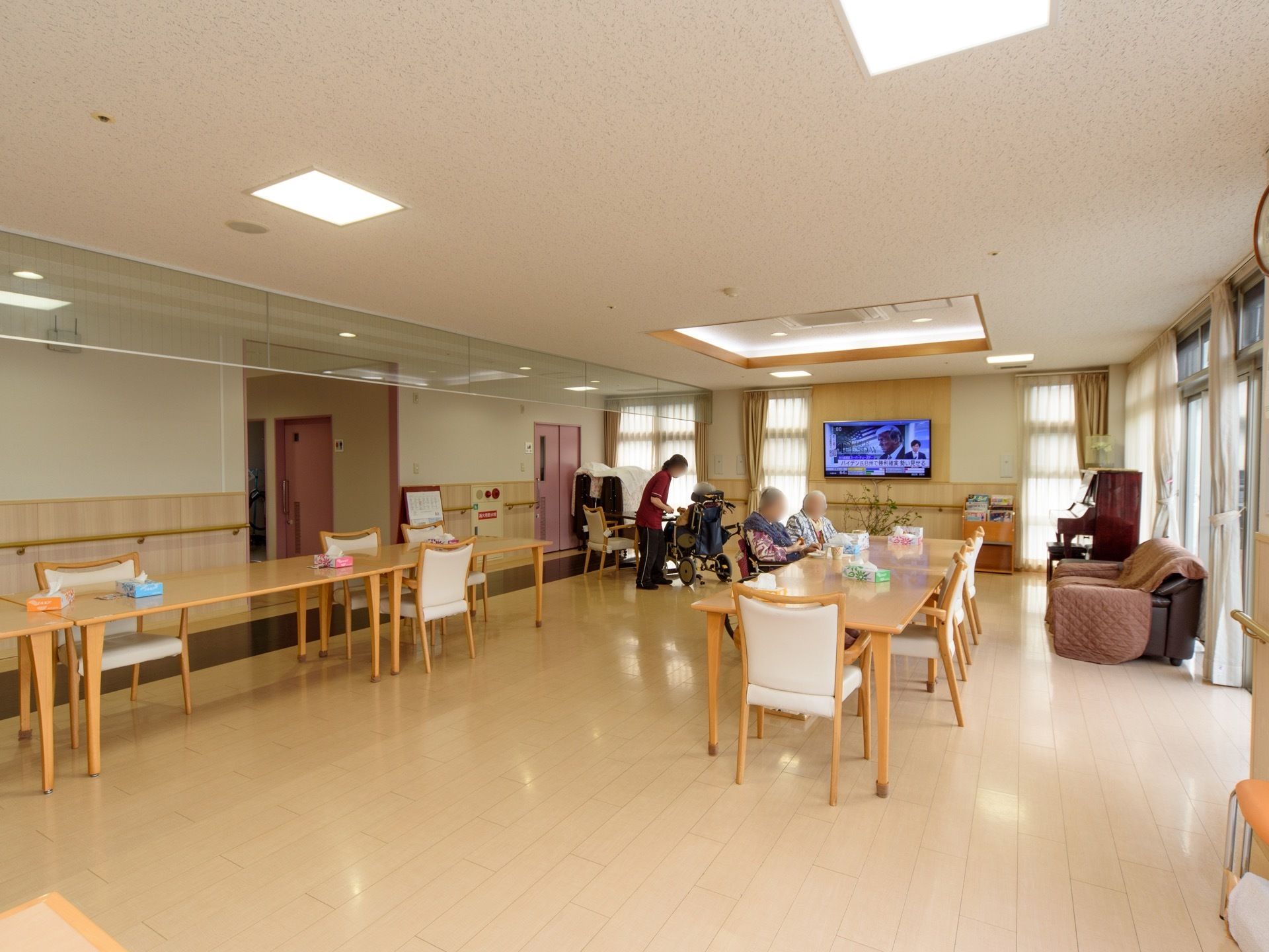 右側の突き当りには、窓が取り付けられており、窓と窓の間にある壁にテレビがある。右側の窓の側には、ピアノやソファーがある。