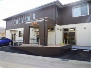 車いす用スロープがついたエントランス。ツートンカラーの清潔感がある建物の外観