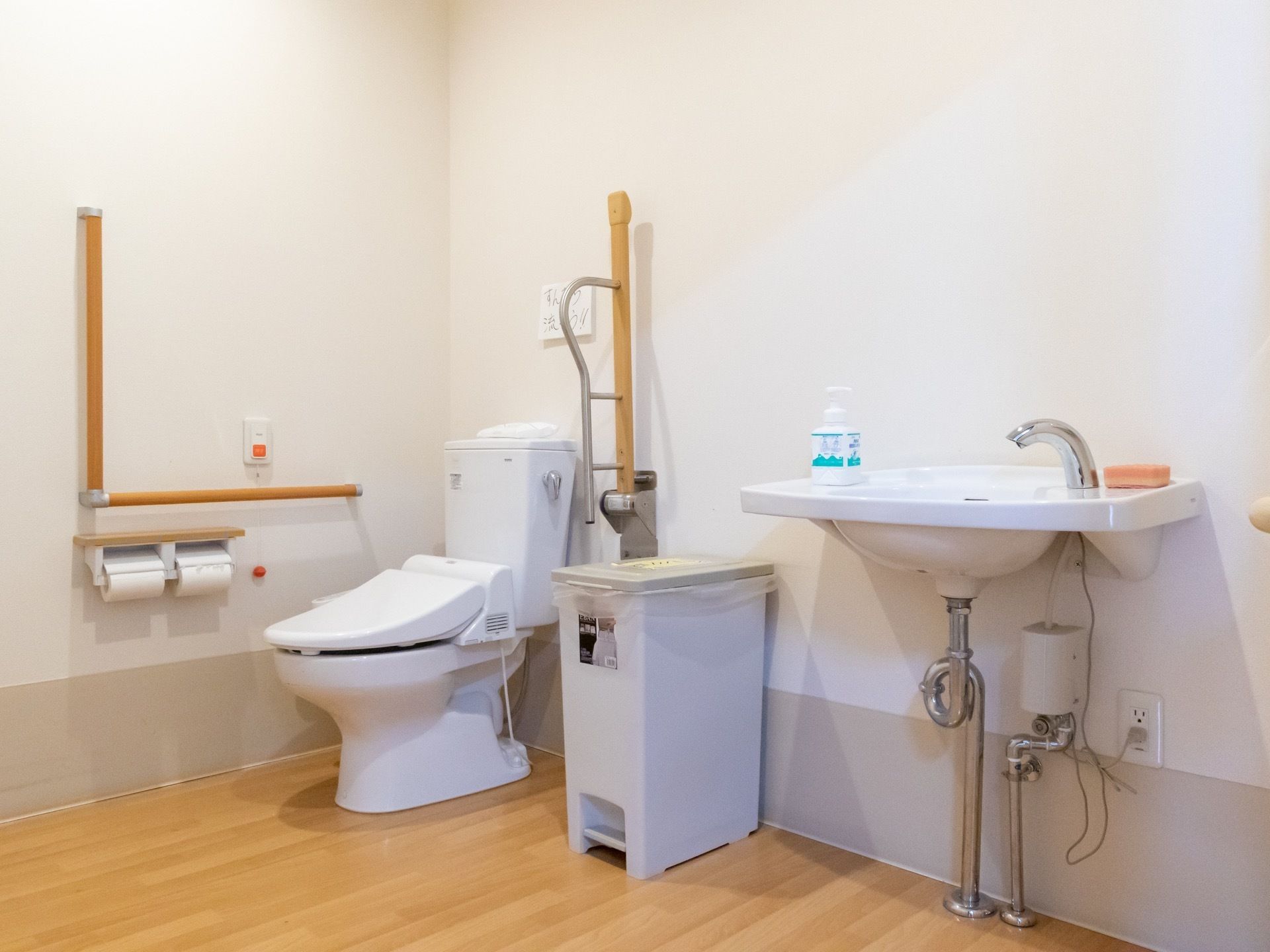 洗面台が完備された多目的トイレである。L型や跳ね上げ式手すり、温水洗浄便座が完備されている。壁には、呼び出しボタンも設置されている。