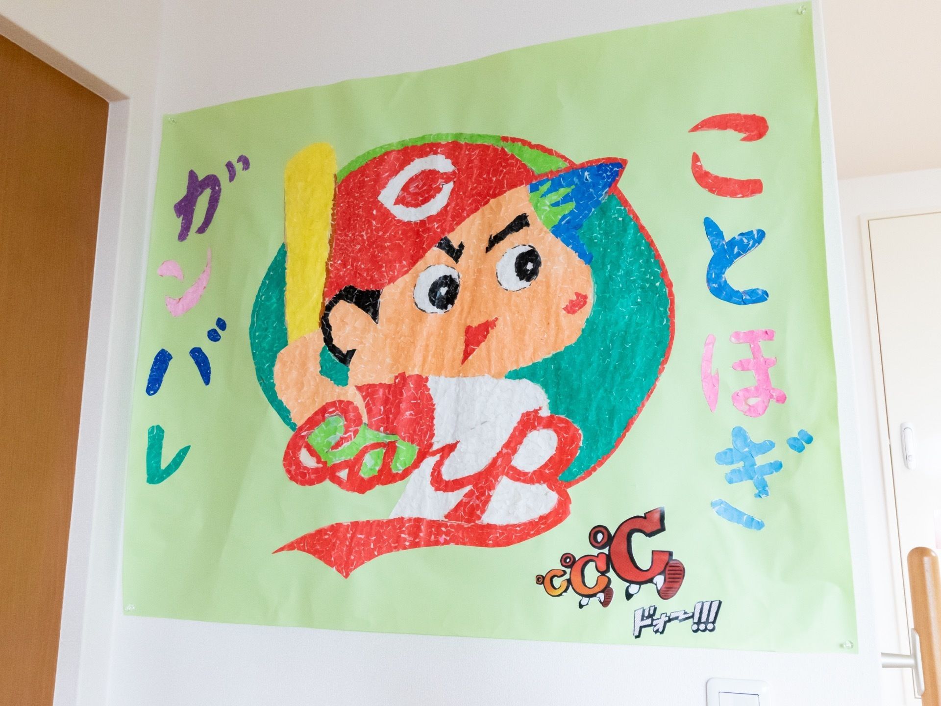 エレベーター横の壁は、にちぎり絵で作った大きなポスターが貼られている。野球少年が上手に表現されている。