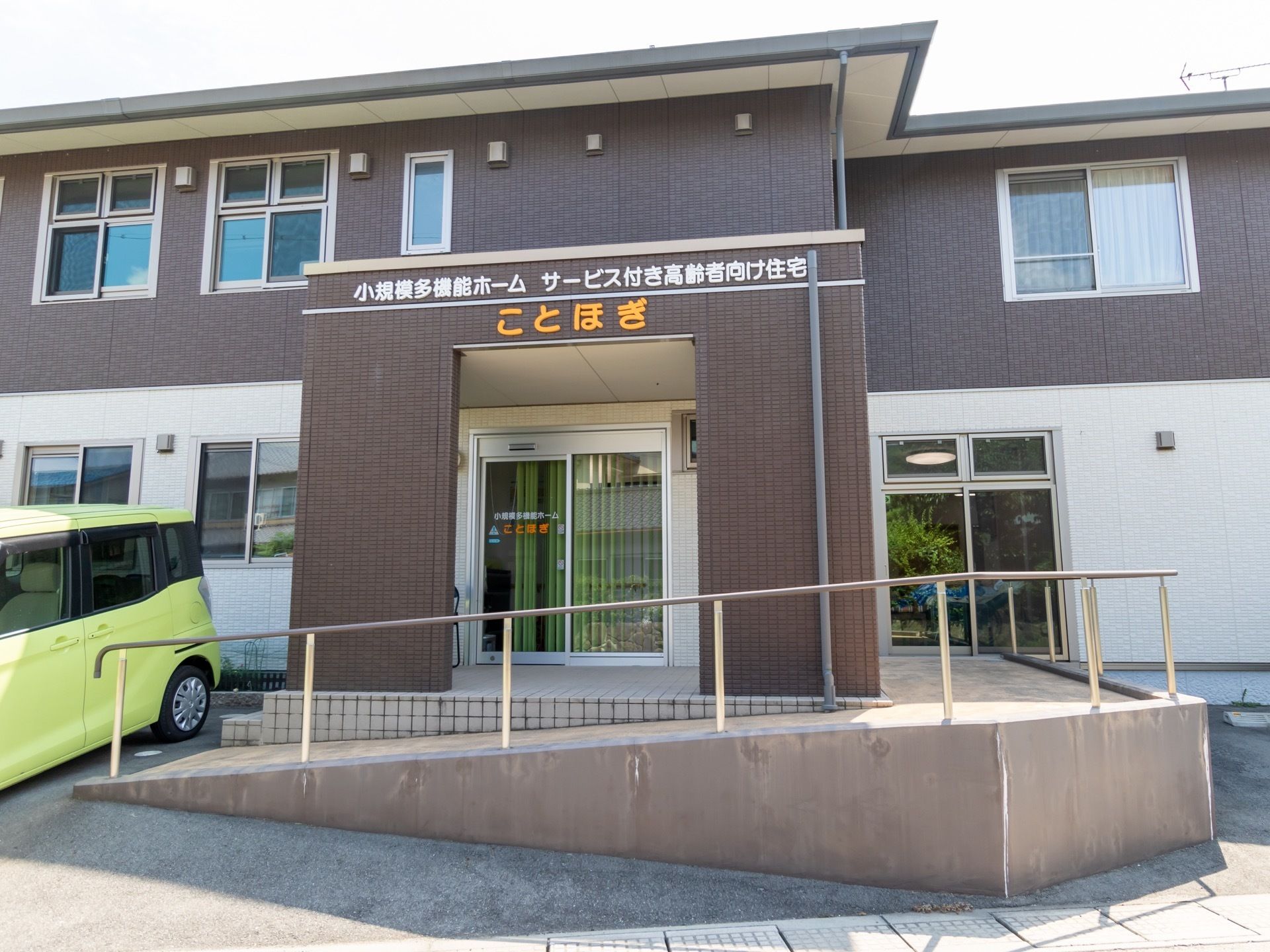 施設は２階建ての建物である。エントランスには、手すり付きのスロープが設けられている。駐車場建物前に用意されている。