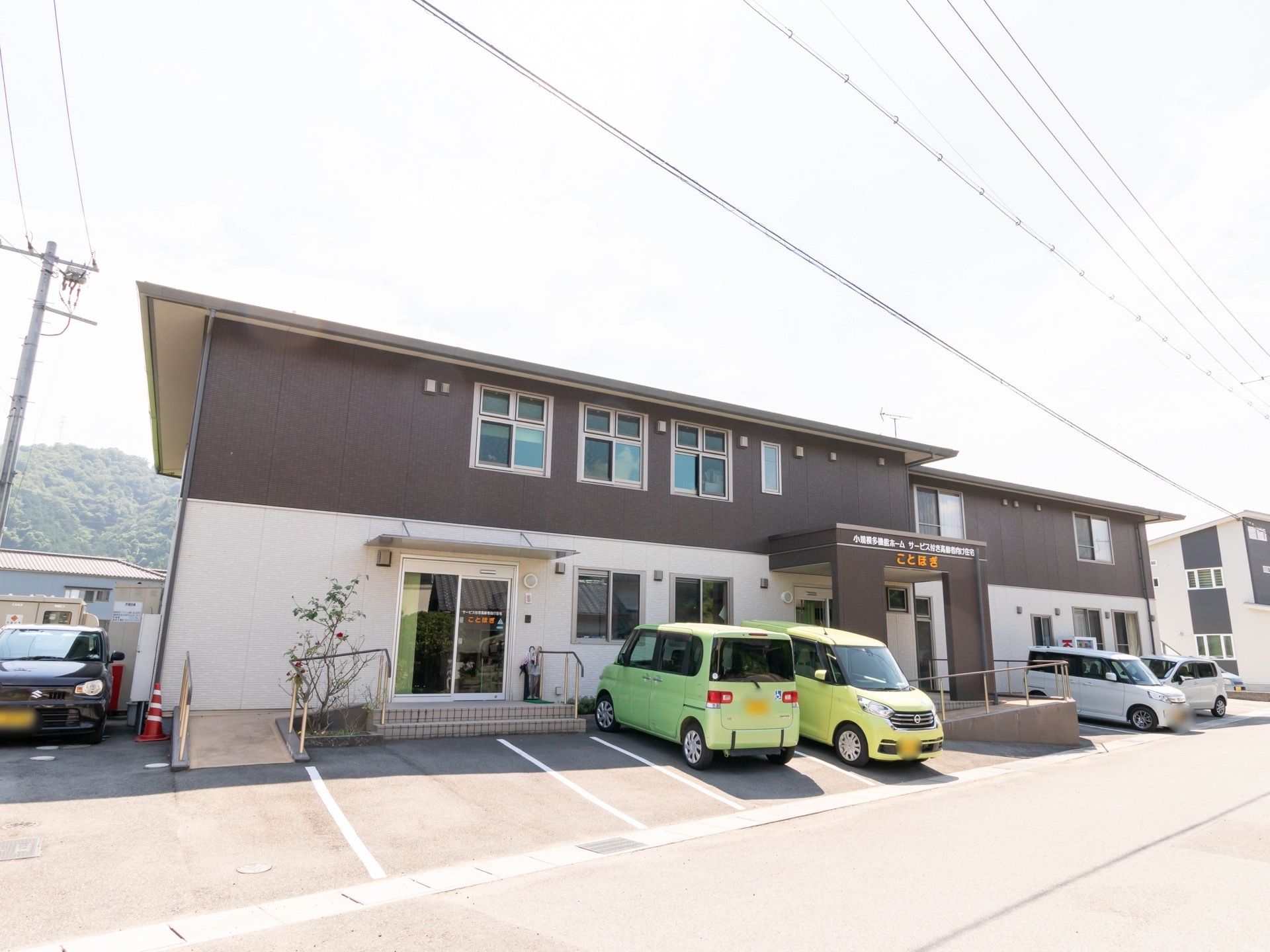 建物の外壁が茶色と白のツートンカラーになっている施設である。建物前に駐車スペースが設けられており、エントランスにスロープがある。