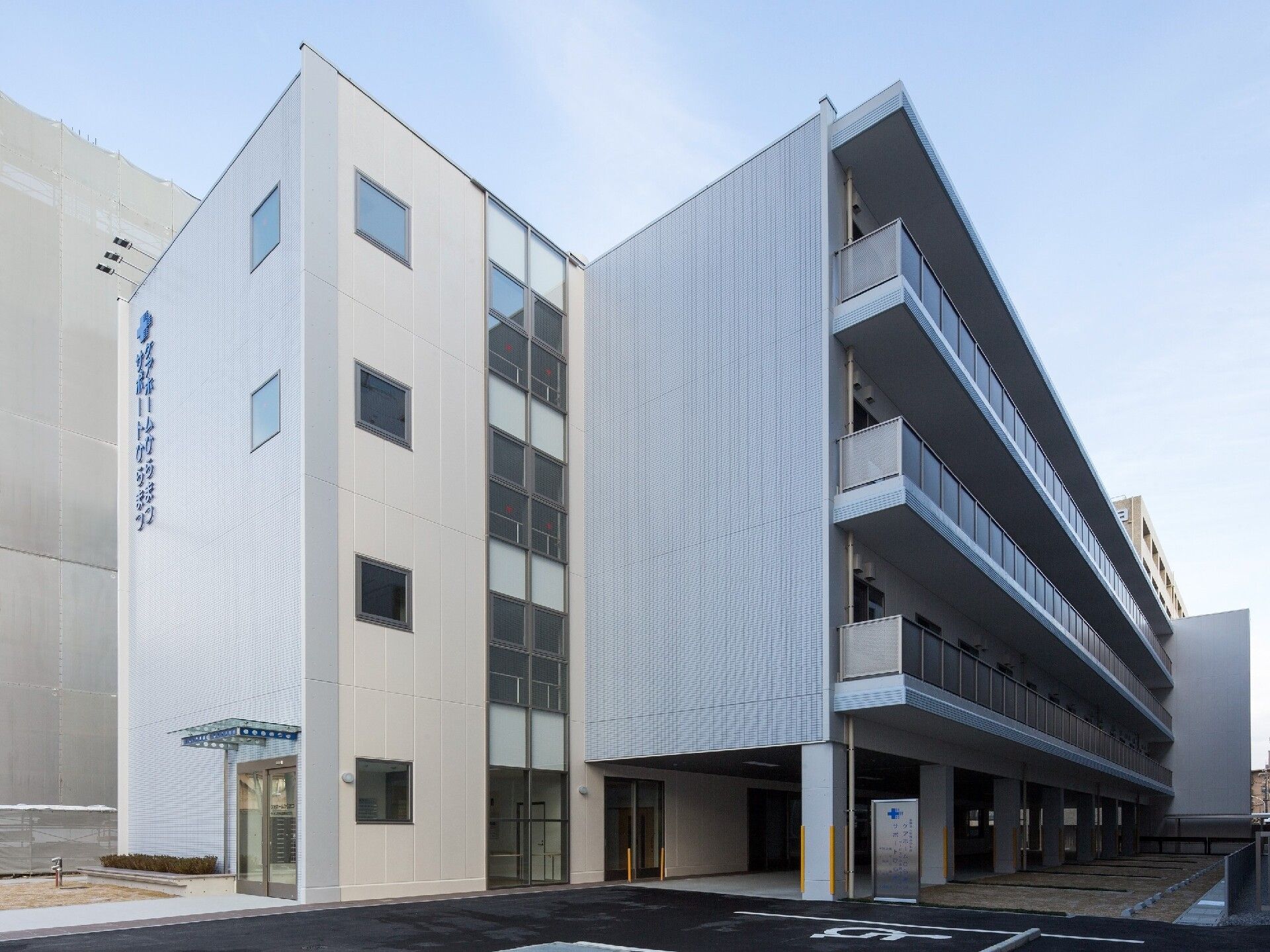 4階建ての建物は各フロアにベランダがあり、敷地内には駐車場があり、玄関には屋根が付いている。
