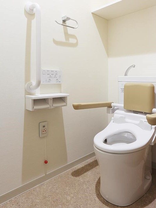 施設内居室のトイレの様子。両側に手すりがあるタイプのトイレの写真