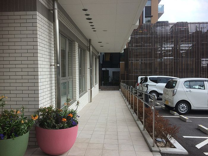 敷地内の駐車場とエントランス付近を写したもの。手前に植物のプランターがある