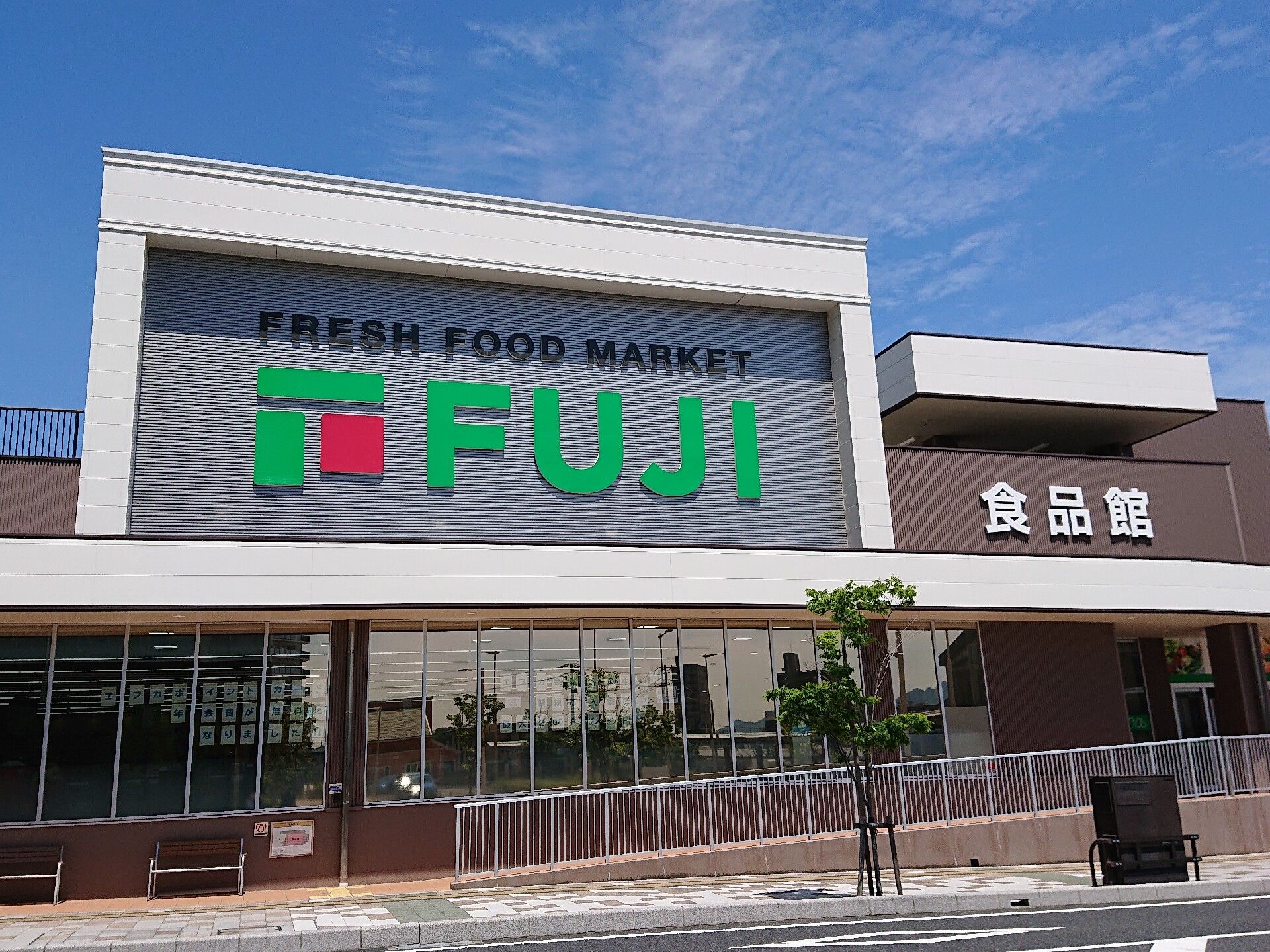 出入り口に手すり付きのスロープが設置されたスーパーマーケット。「FUJI　食品館」と書かれている。
