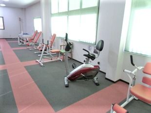 大きな窓がたくさんついたスペースに並べられたリハビリ器具。