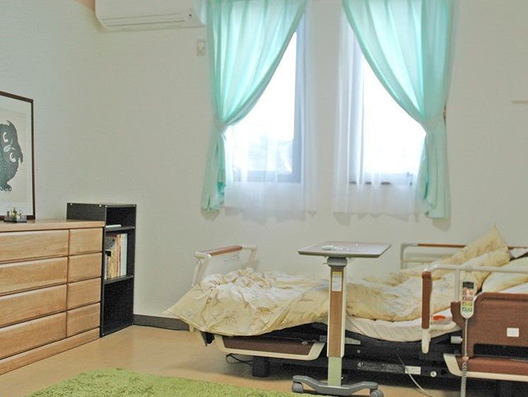 収納家具やエアコンが設置された広い居室にはベッドも置かれている。