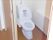 スライド式のドアが設置されたトイレは広く、温水便座が設置され、トイレットペーパーホルダーもある。