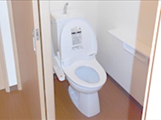 トイレは温水便座付きで、トイレットペーパーホルダーも壁にあり、スライド式のドアが設置されている。