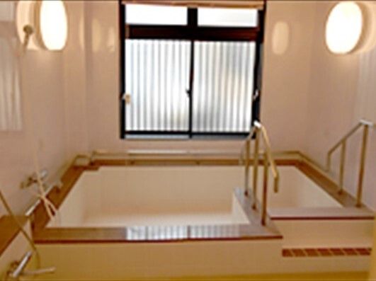 大きなすりガラスの窓が付いた浴室内は明るく、大きな浴槽の出入り口には手すりが付いている。