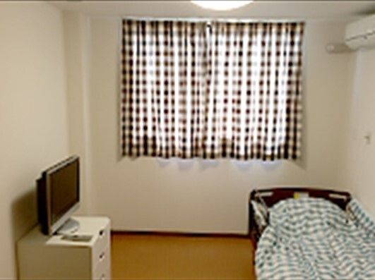 エアコン付きの部屋にはテレビや寝具付きのベッドが置かれ、窓にはカーテンも付いている。