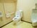広いトイレにはエル字型の手すりが壁につき、呼び出しボタンもある。男性用小便器も設置されている。