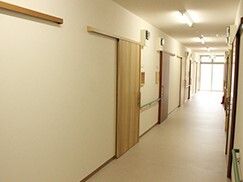 スライド式のドアが設置された居室が両サイドに並んでいるまっすぐな廊下。