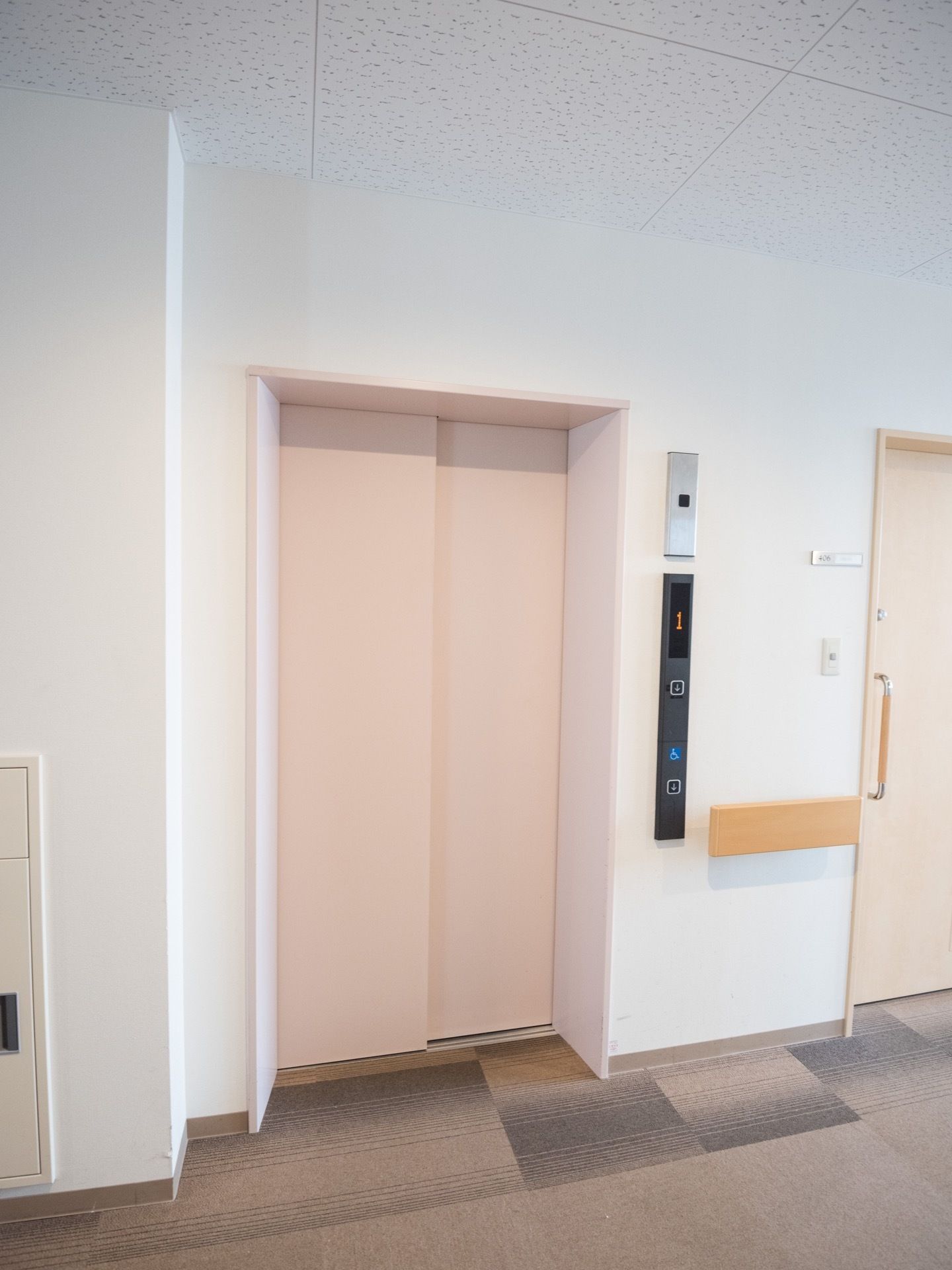 ベージュのエレベーターで間口が広い。天井や壁は白で統一されており、開放的な空間である。廊下は段差がなく安心して通行できる。