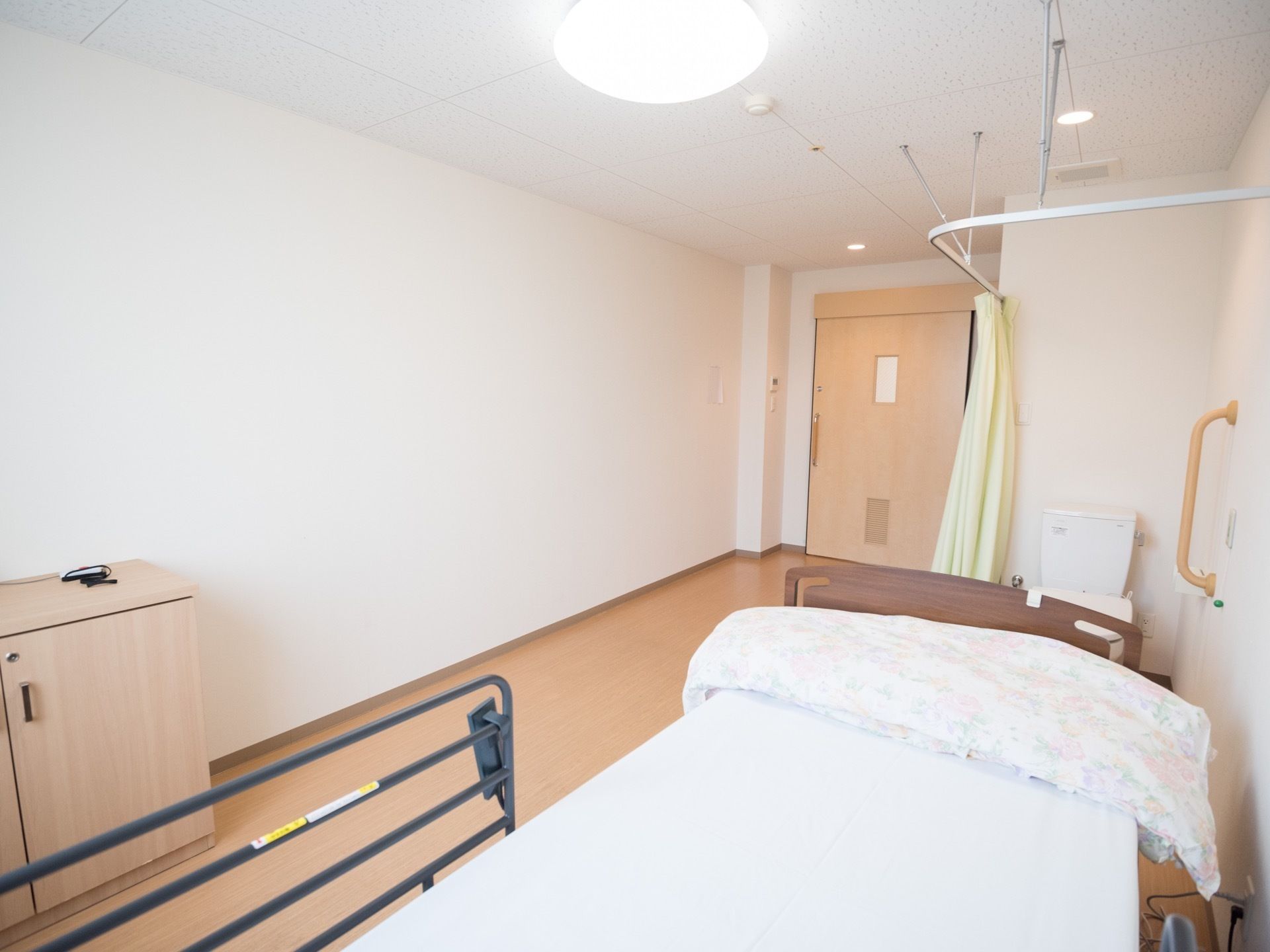 間口の広い横開きの扉である。壁と天井が白で統一された明るく開放的な空間に、ベッドや家具が置かれている。