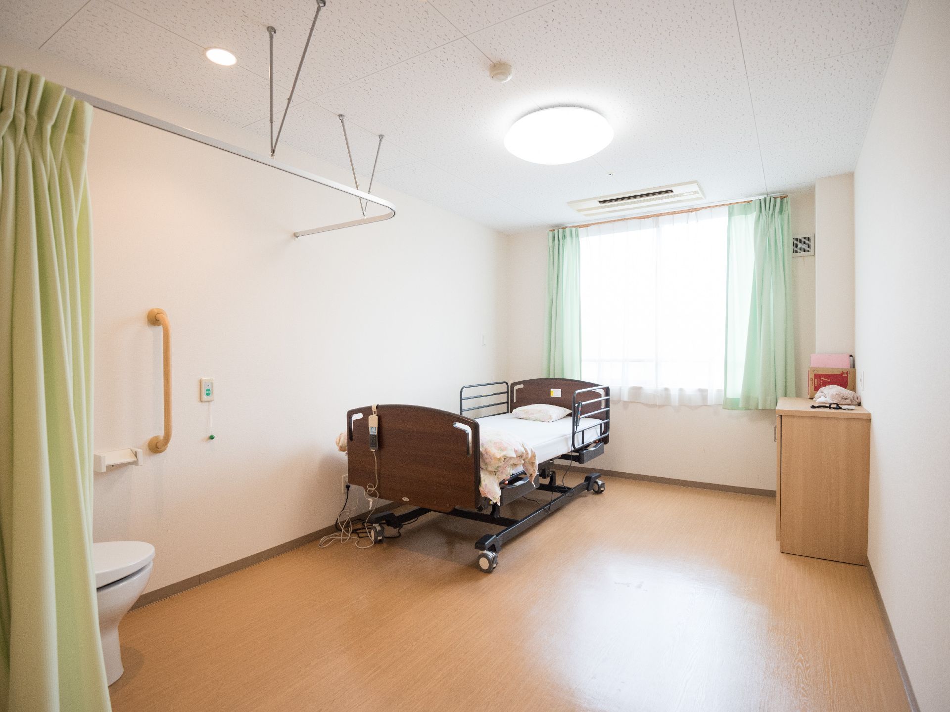 居室内のベッドとトイレの写真。介護用ベッドが写っている