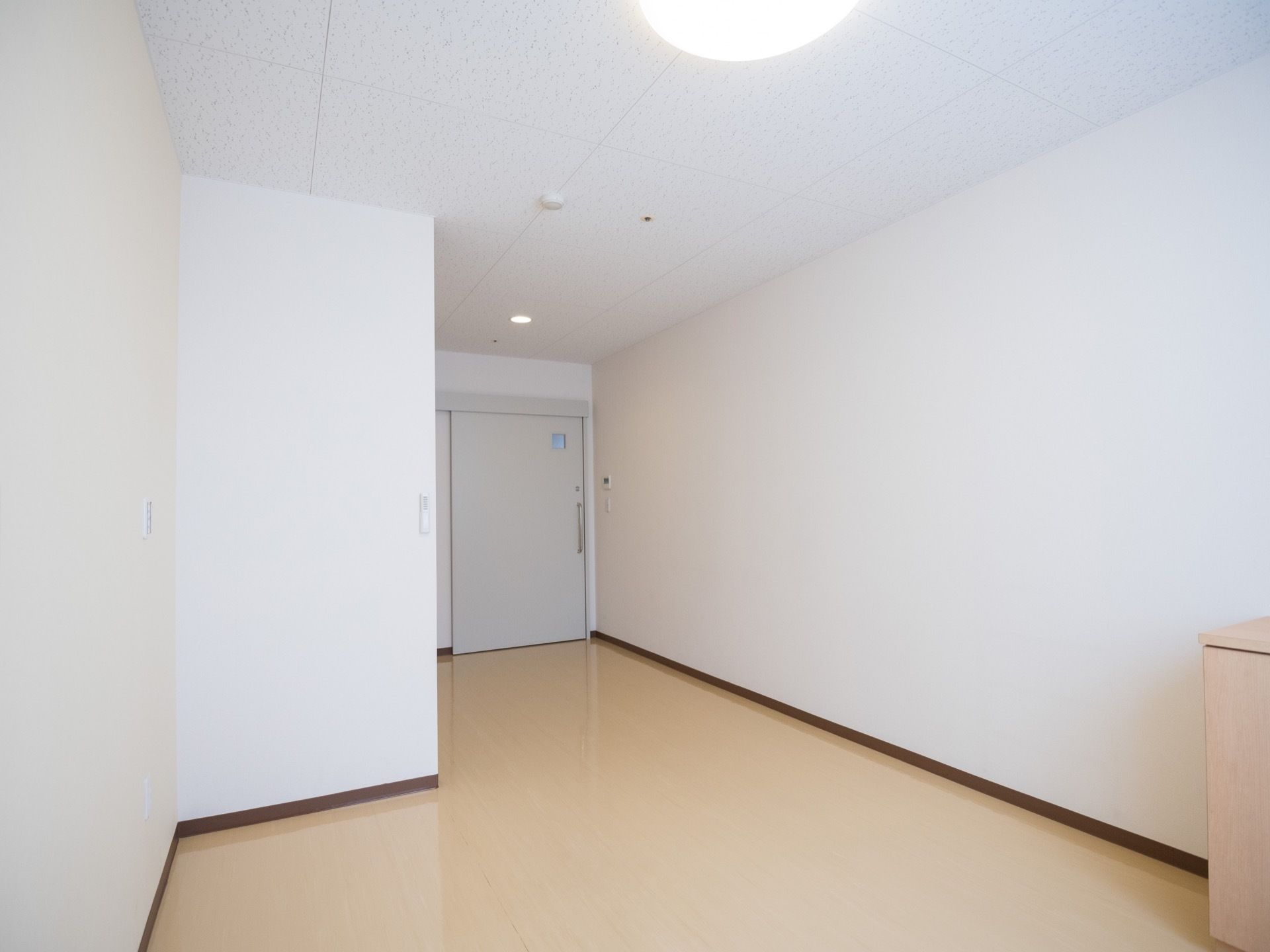 大きな引き戸の出入り口が取り付けられている奥行きのある個室である。艶のあるクリーム色の床が施されている。