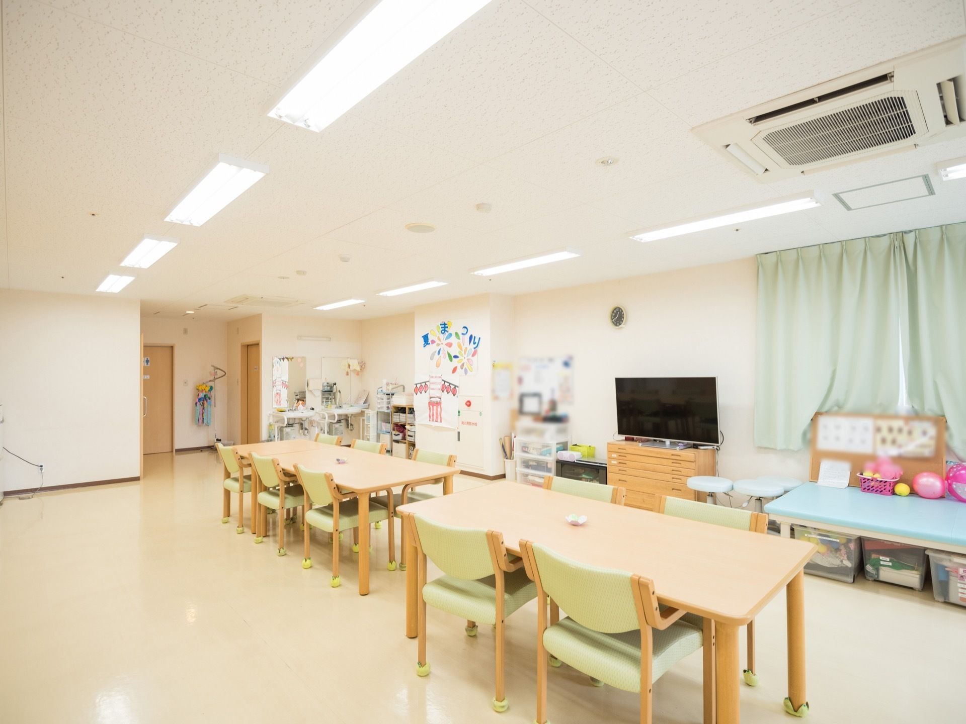 脚にテニスボールがはめられたテーブルや椅子が並べられている広間。イベントに関する壁面装飾が施されている。