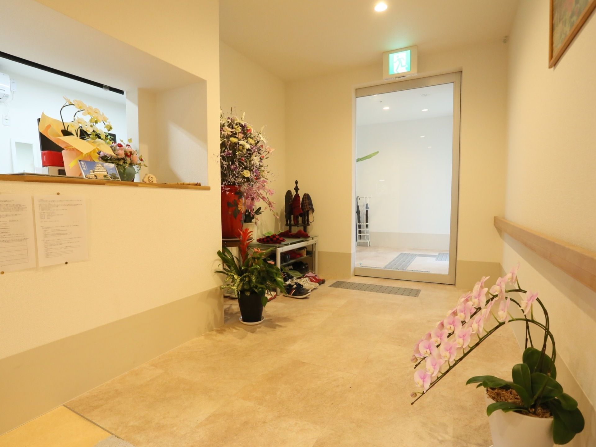 玄関は大きなガラスの自動ドアになっている。ドアの内外に展示ブロックが設置されている。きれいな花が咲いている鉢がいくつか置かれている。