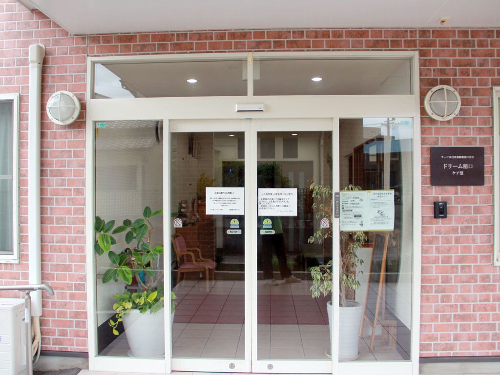 大きめのガラス戸の自動ドアが設置され、中にある観葉植物やいすが良く見える。