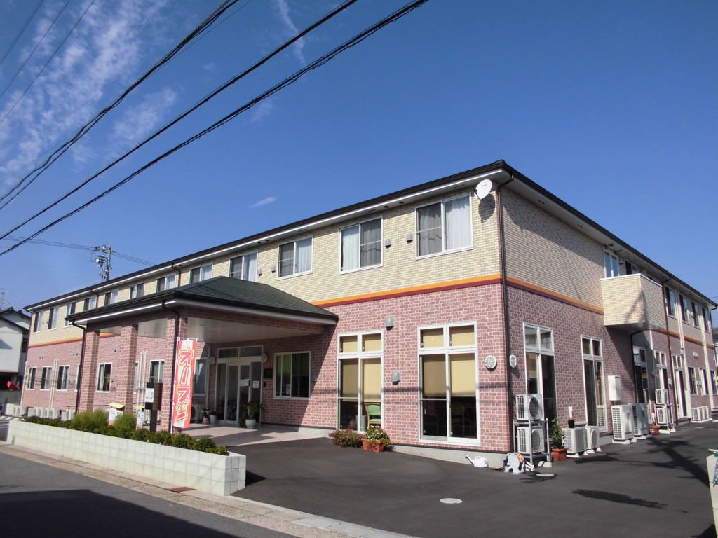 横に長い２階建ての建物。玄関についた大きな車寄せの横には「オープン」と書かれた旗がゆらめいている。