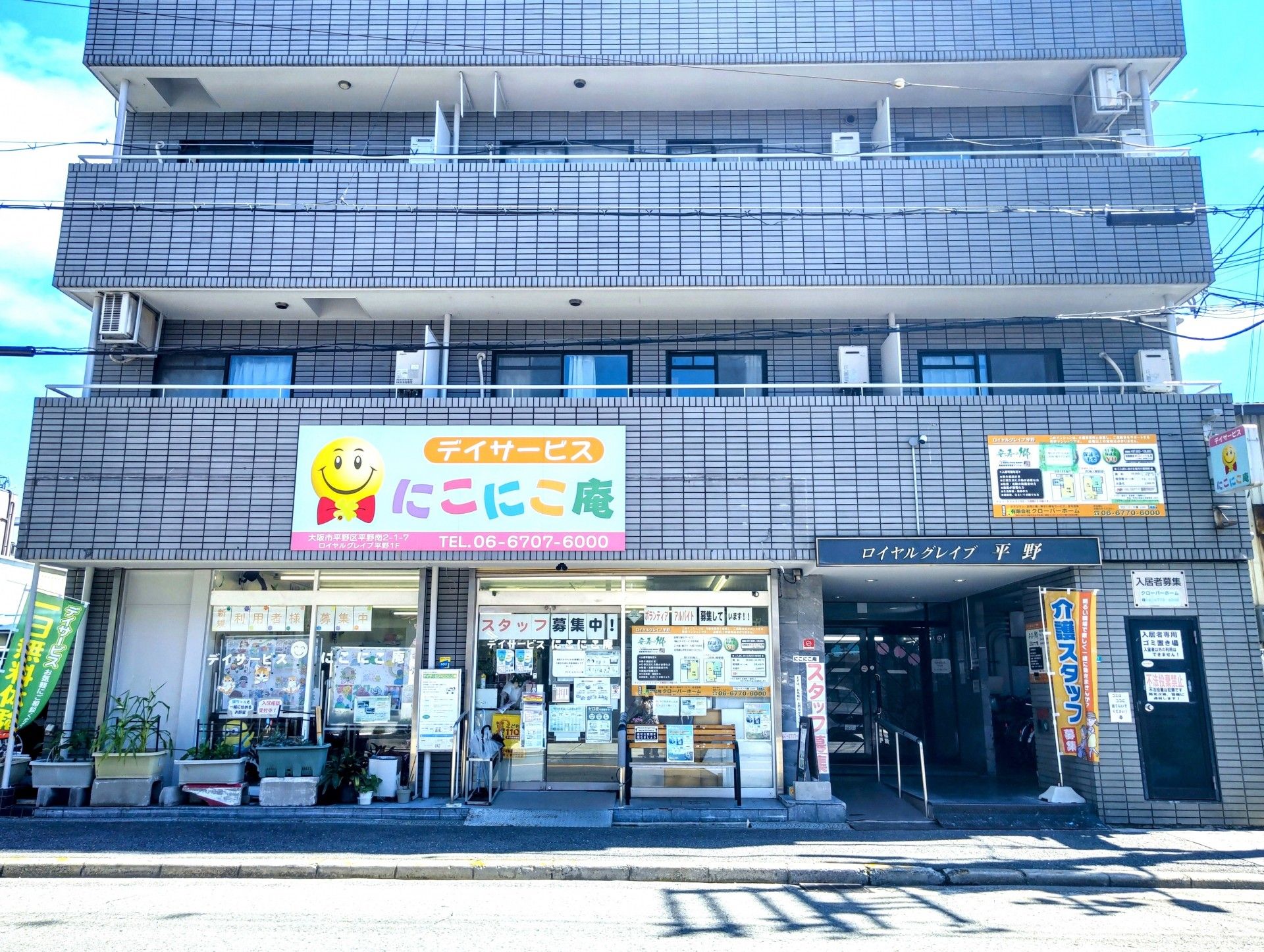 グレーのタイルが貼られたマンションのような施設である。１階部分にはデイサービスが入居している。右手に入口がある。