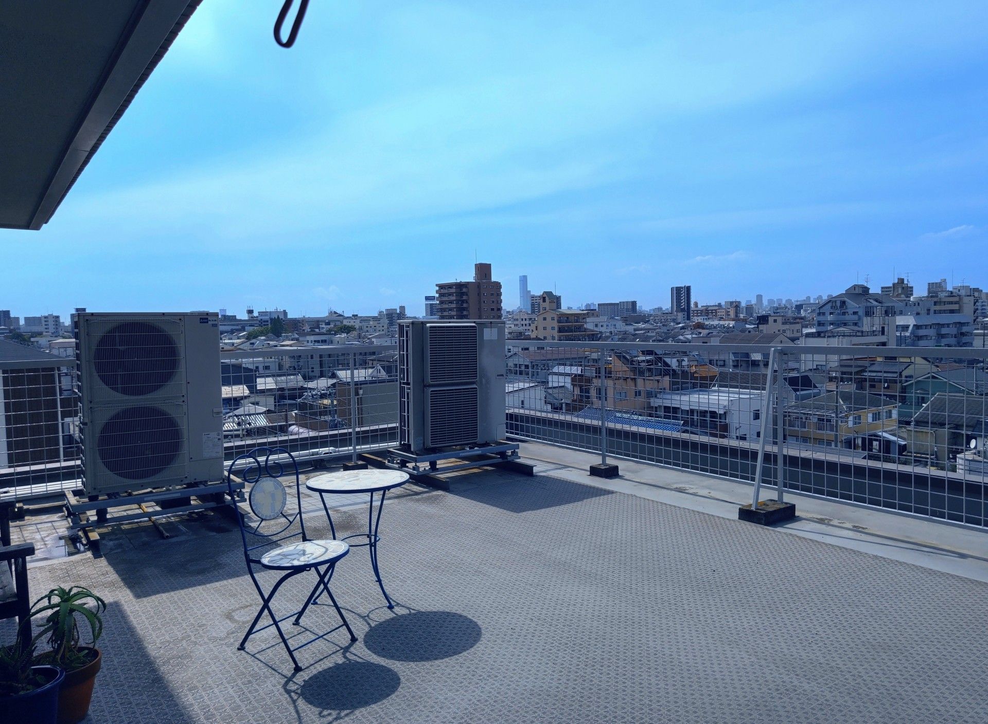 施設の屋上から見える近隣の景色の写真である。どこまでも住宅街が広がり、左側にはうっすらと山が見えている。