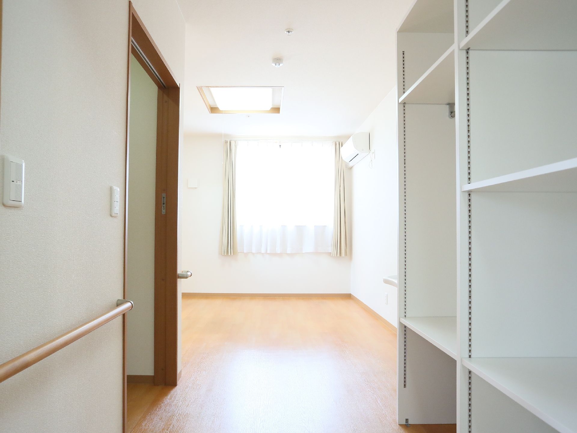 入口付近に棚が取り付けられていて、手すりのある明るい居室