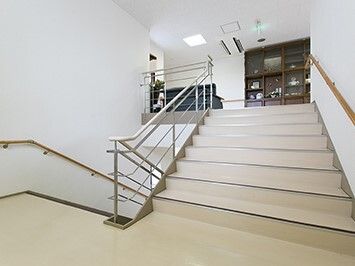 手すりが両サイドに設置された階段。階段の幅が広く、踊り場も広く、ベージュで明るい雰囲気。