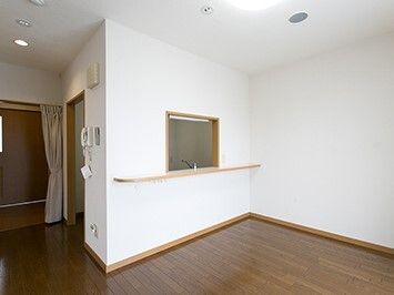 フローリングの部屋には家具はなく、壁には受話器が設置され、キッチンとの間にはカウンターがある。