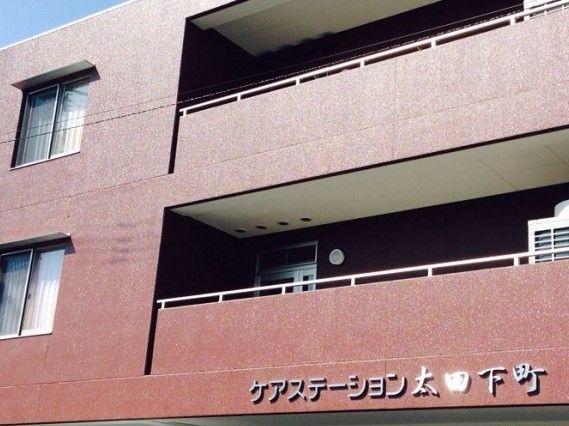 住宅の名前が書かれた外壁。ブラウンの建物は各フロアにベランダが付いている。