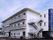 屋外階段が付いた白い３階建ての建物。各フロアにはベランダがあり、駐車スペースも付いている。