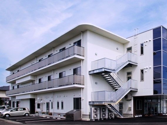 ３階建ての建物は白を基調としていて、屋外階段やベランダ、駐車場が付いている。