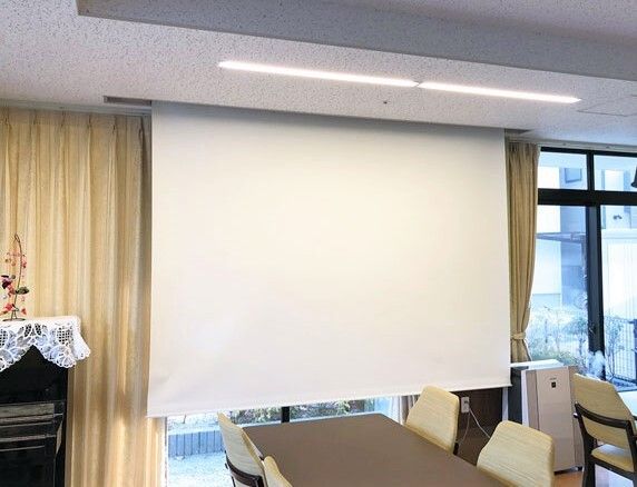 大きな窓のそばには収納できるスクリーンが設置されている。共有スペースにはダイニングテーブルだけでなくピアノもある。