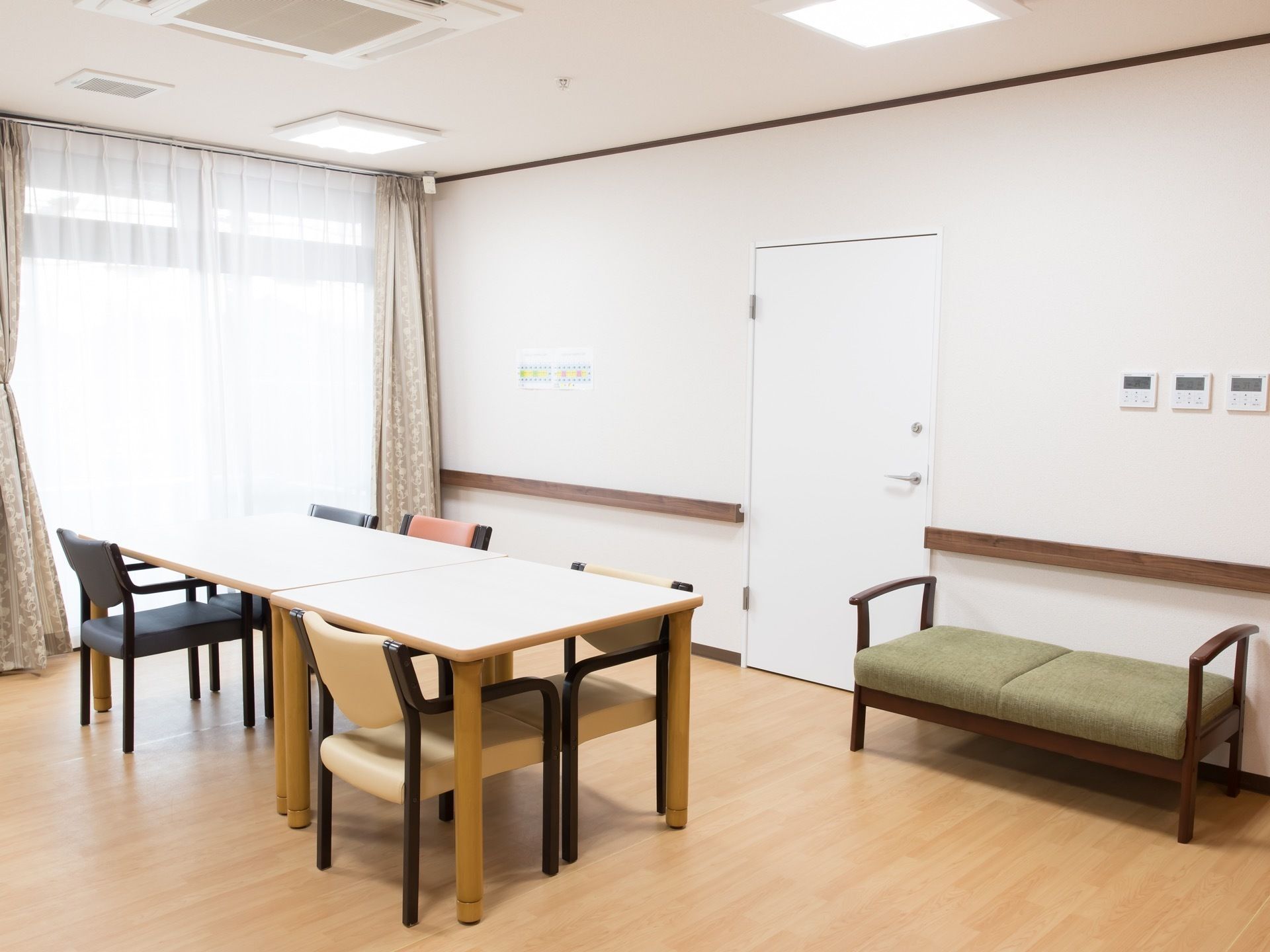 外光がたっぷりと降り注ぐ明るい空間。壁には空調の操作パネルが複数設置されており、床は木目調のフローリングとなっている。