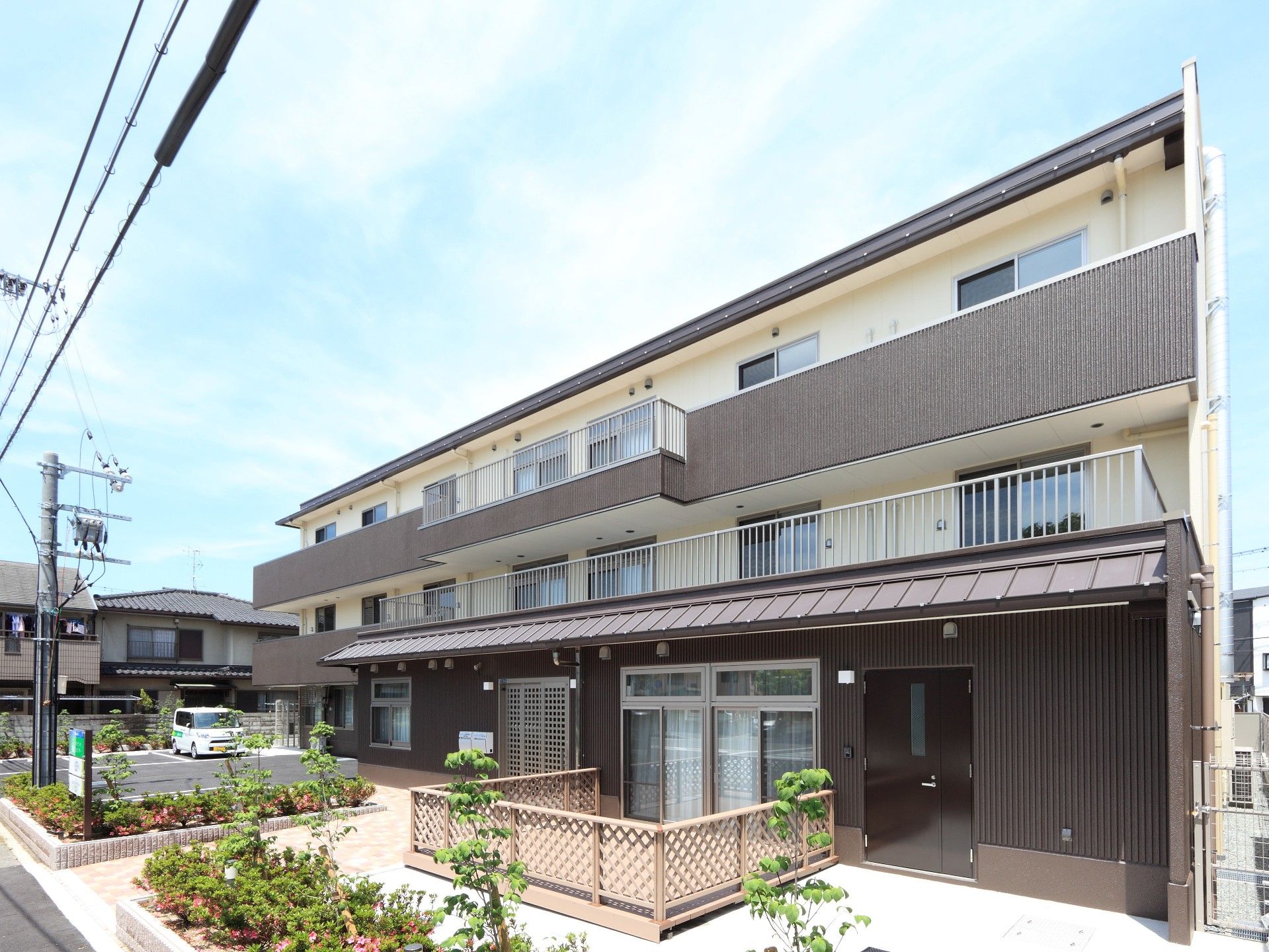駐車スペースがある3階建ての建物にはウッドデッキやベランダも付いている。
