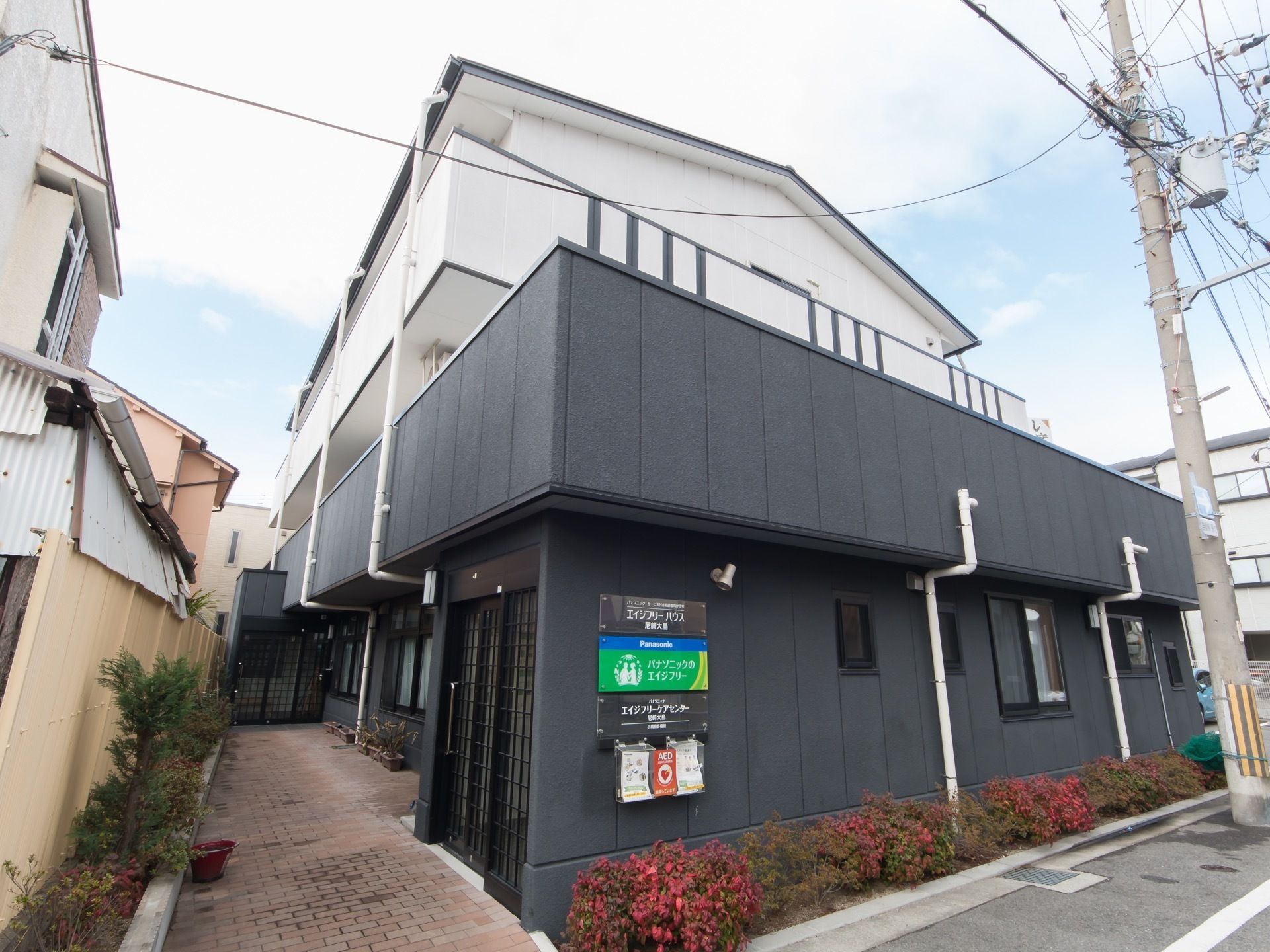 施設は白と黒の外壁が特徴的な３階建ての建物である。玄関アプローチには、タイルが敷かれいる。塀に沿って花壇が設けられている。