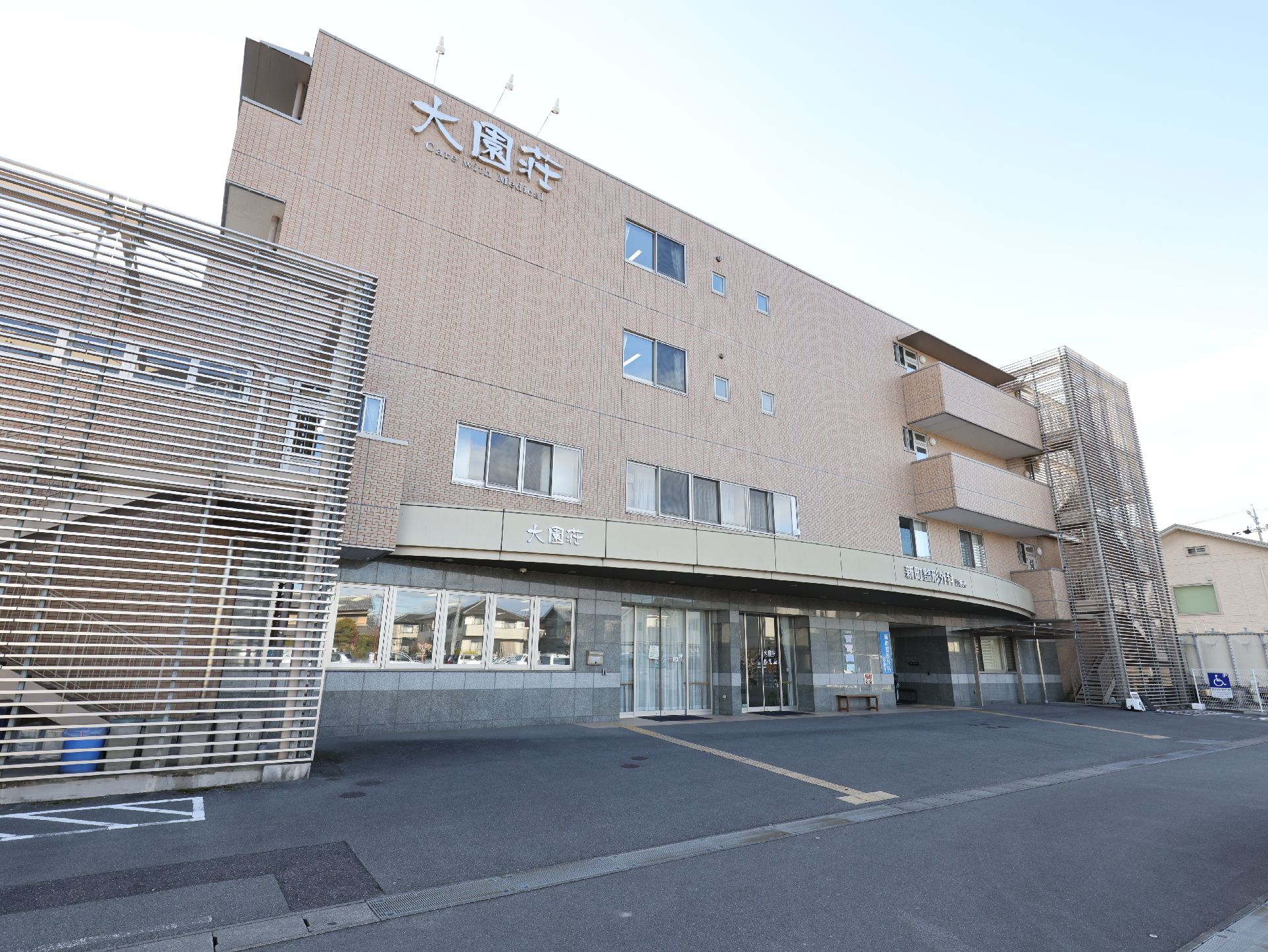 車いすに乗る女性と笑顔でそれを押すスタッフ。二人で散歩しながら会話している様子