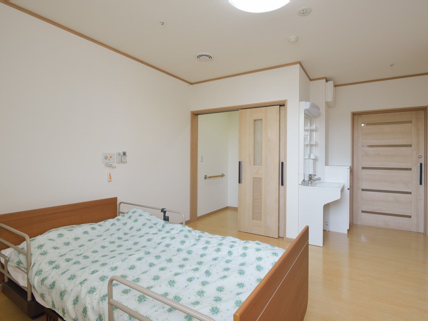 大きなベッドが設置されたフローリングの居室にはトイレや洗面所もある。