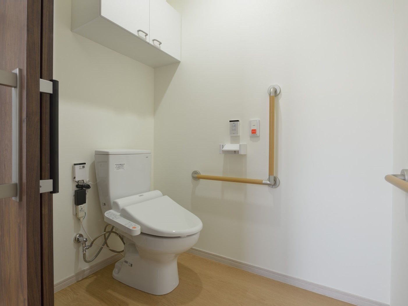トイレはシンプルなデザインで、壁には呼び出しボタンや収納棚、手すりが付いている。